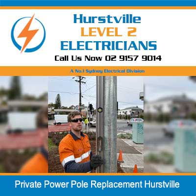 Electrician in safety gear replacing concrete power pole on street in Hurstville